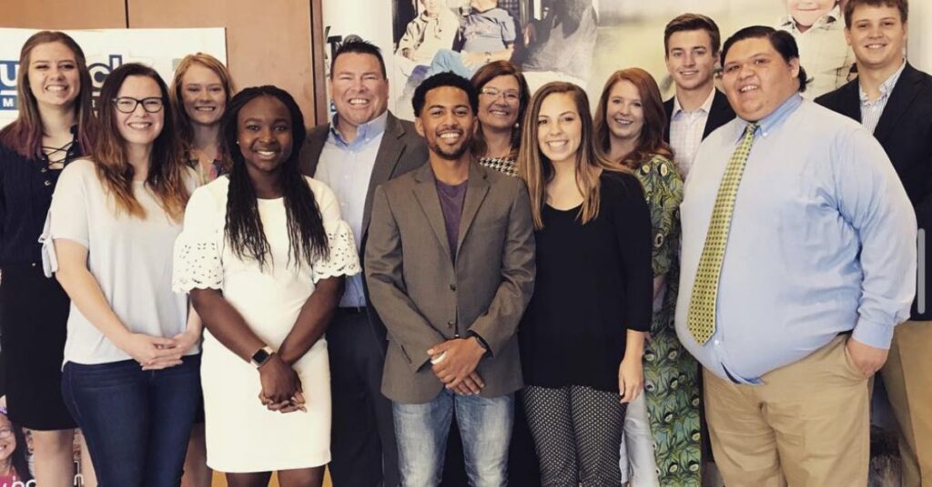 summer internship for at risk youth, posing and smiling alongside fellow interns in business casual dress