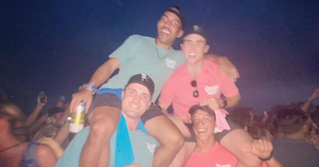 four friends, two on top of the others shoulders posing in the crowd of Austin city limits 2022