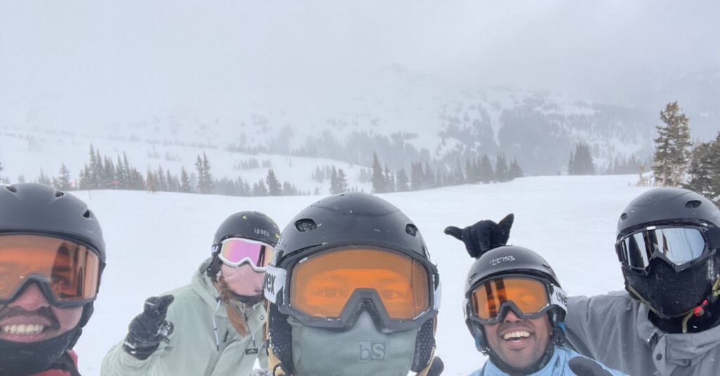 5 people on a mountain top during the winter with snowboard gear on
