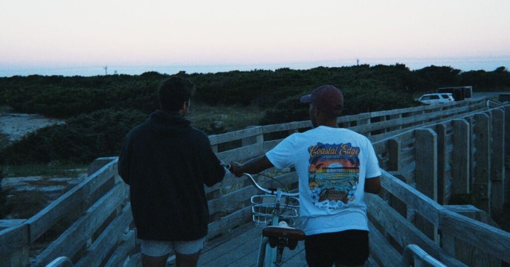 two friends after a sunset walking on beach wooden walkways