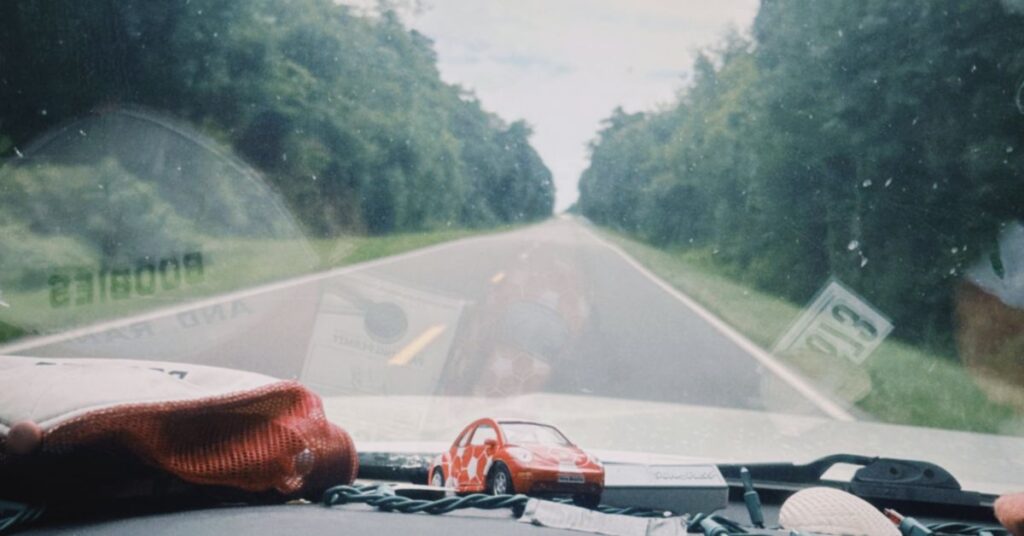 traveling a car, window view of road and green trees surrounding the road