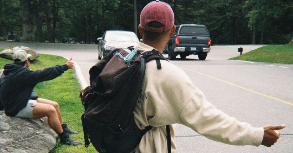 two friends holding out thumb to hitchhike